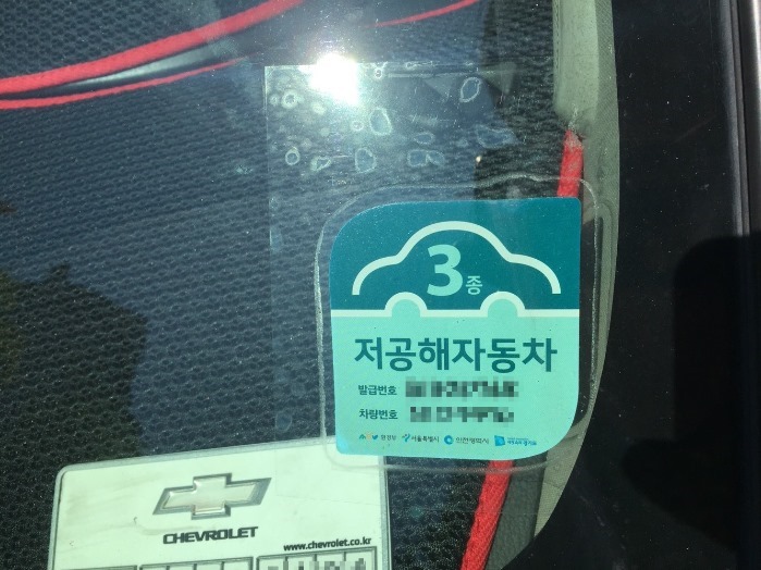  저공해자동차스티커에 코팅지를 붙였다