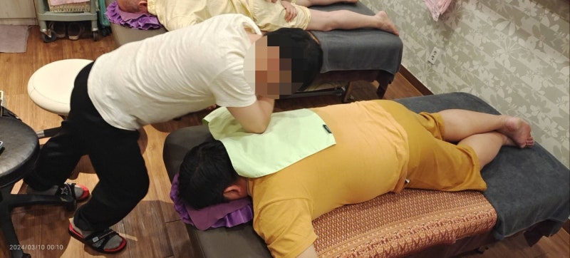 오픈 형태의 대형 관시실에서 남성 관리사가 고객의 등근육을 풀어주는 모습