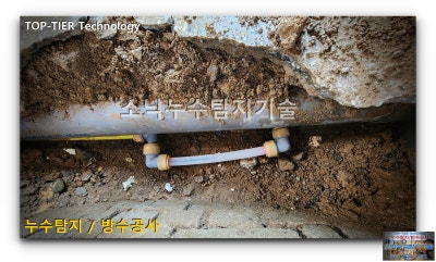 굵은 배수관 아래를 지나는 급수 배관을 새 자재로 이어 수리한 상태