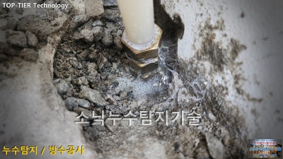 굴착한 홈 안의 흰색 배관과 황동 이음부 둘레에 비눗물 거품이 하얗게 맺힌 누수 지점 확인 장면