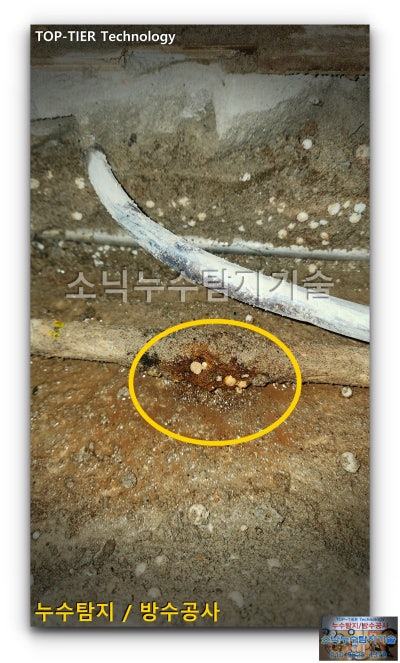 바닥을 걷어낸 자리에 드러난 배관과 노란 원 안으로 비눗물 거품이 올라온 온수배관 누수 지점