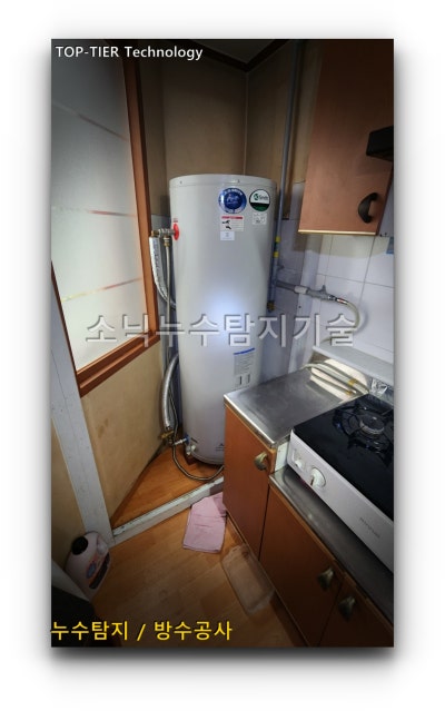누수 피해 지점 바로 위층 주방 옆 좁은 공간에 벽에 붙여 설치된 흰색 원통형 심야 온수기와 연결 배관