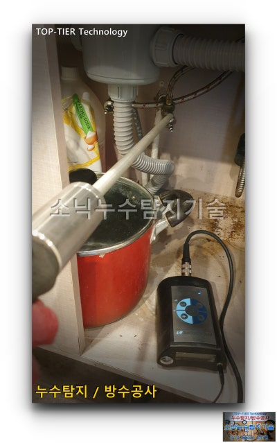 카페 주방 싱크대 하부 배관에 청음 탐지봉을 대고 옆에 놓인 청음기 본체로 소리를 확인하는 모습