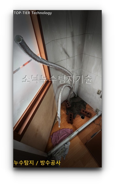 연결 부속을 교체한 뒤 동파에 대비해 보온재로 다시 감싼 배관 두 가닥이 벽 모서리를 따라 올라간 모습