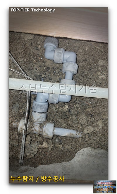 좁게 열어 놓은 바닥 안에서 연결 부속을 살린 채 새 배관으로 교체한 모습