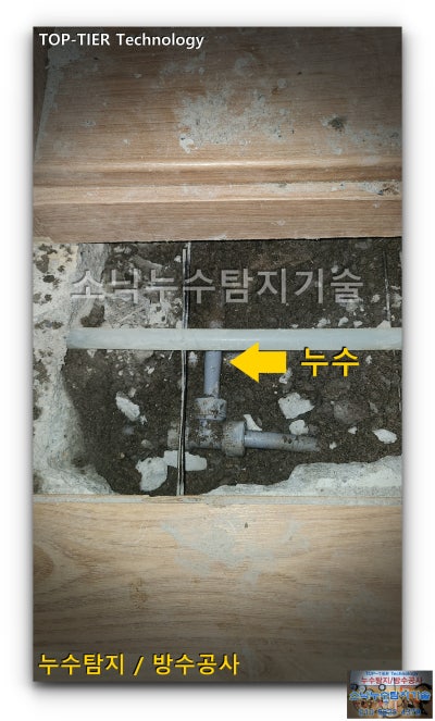 굴착한 바닥 속에서 드러난 회색 급수배관과 누수 위치를 가리키는 화살표 표시