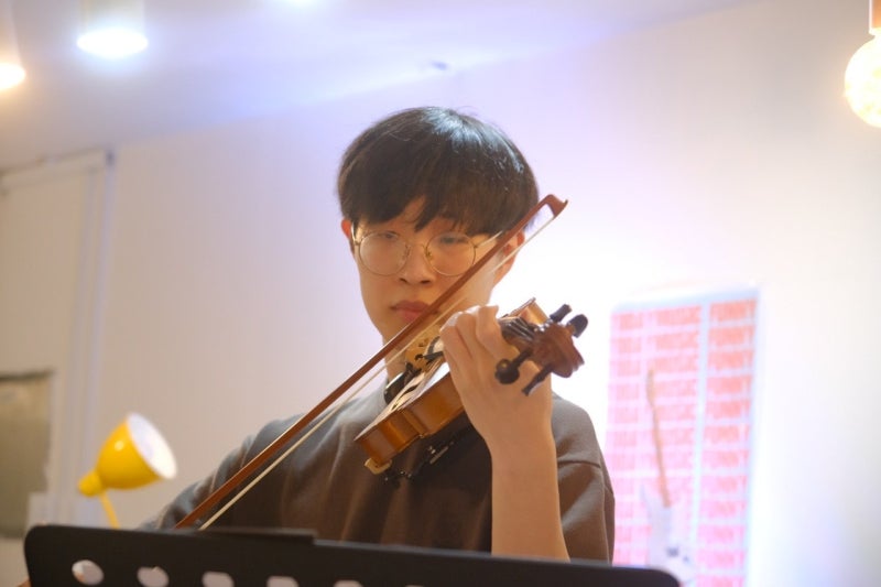 오늘은뮤직 안산점에서 안경을 쓴 수강생이 보면대 앞에서 바이올린 활을 긋는 모습