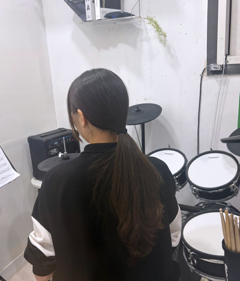 오늘은뮤직 부산점 드럼 레슨실, 드럼 세트 앞에서 스틱을 쥔 모습