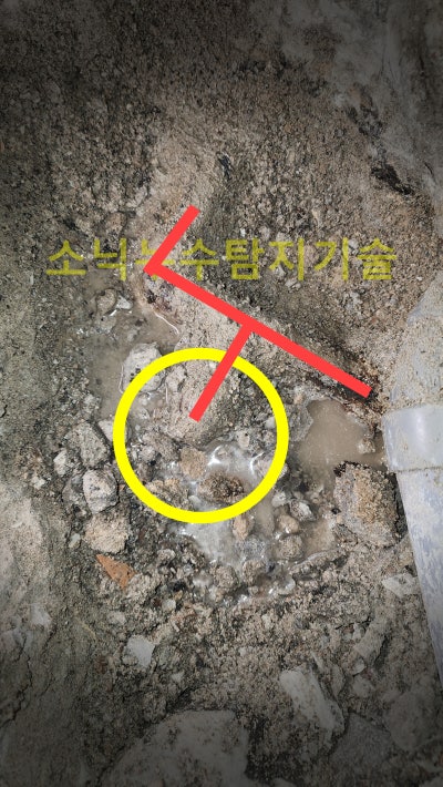 굴착한 화장실 바닥에서 젖어 있는 지점을 원과 선으로 표시해 배관 위치를 나타낸 장면