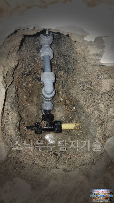 좁게 굴착한 자리에서 부속으로 다시 이은 급수배관과 오른쪽으로 이어진 노란색 PPC 배관