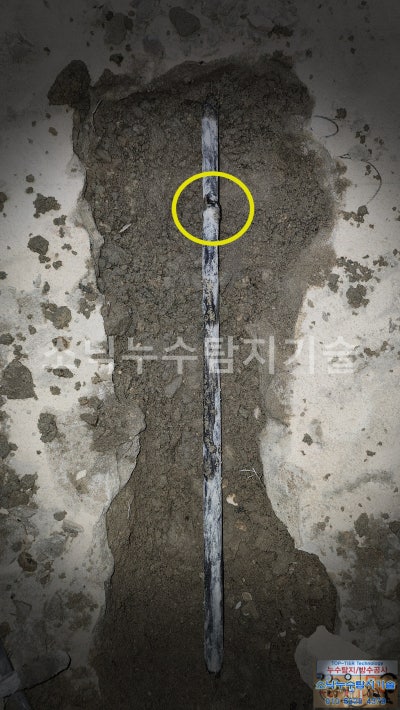 방바닥을 일자로 길게 굴착해 드러난 난방 동배관과 노란 원으로 표시한 용접부 누수 지점