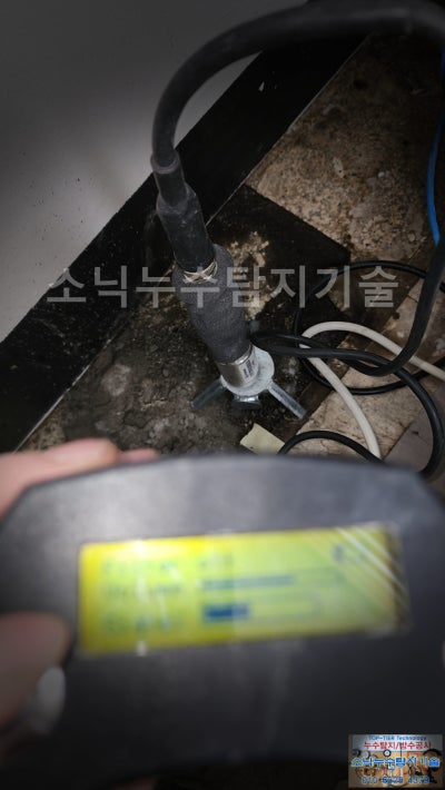 서버실 바닥 데코타일 위에 청음 센서를 세워 두고 누수음을 듣는 모습, 옆으로 배선이 지나간다