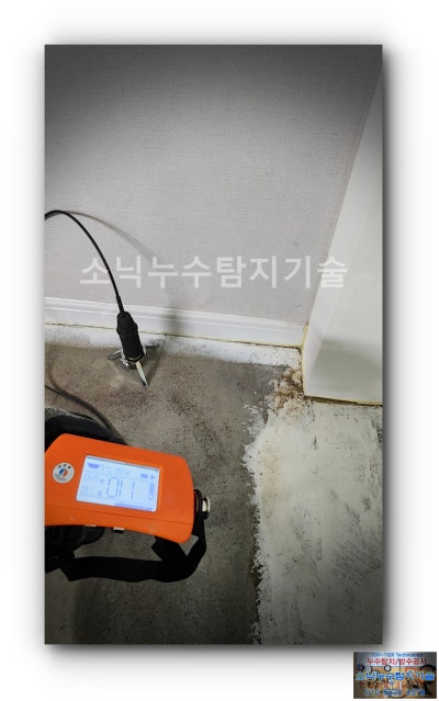 장판을 걷어낸 거실 바닥 걸레받이 앞에 청음 센서를 대고 수신기 화면을 보며 소리를 확인하는 모습