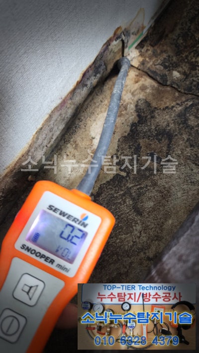 벽과 바닥이 만나는 자리에 청음 센서를 대고 난방 누수음을 확인하는 모습